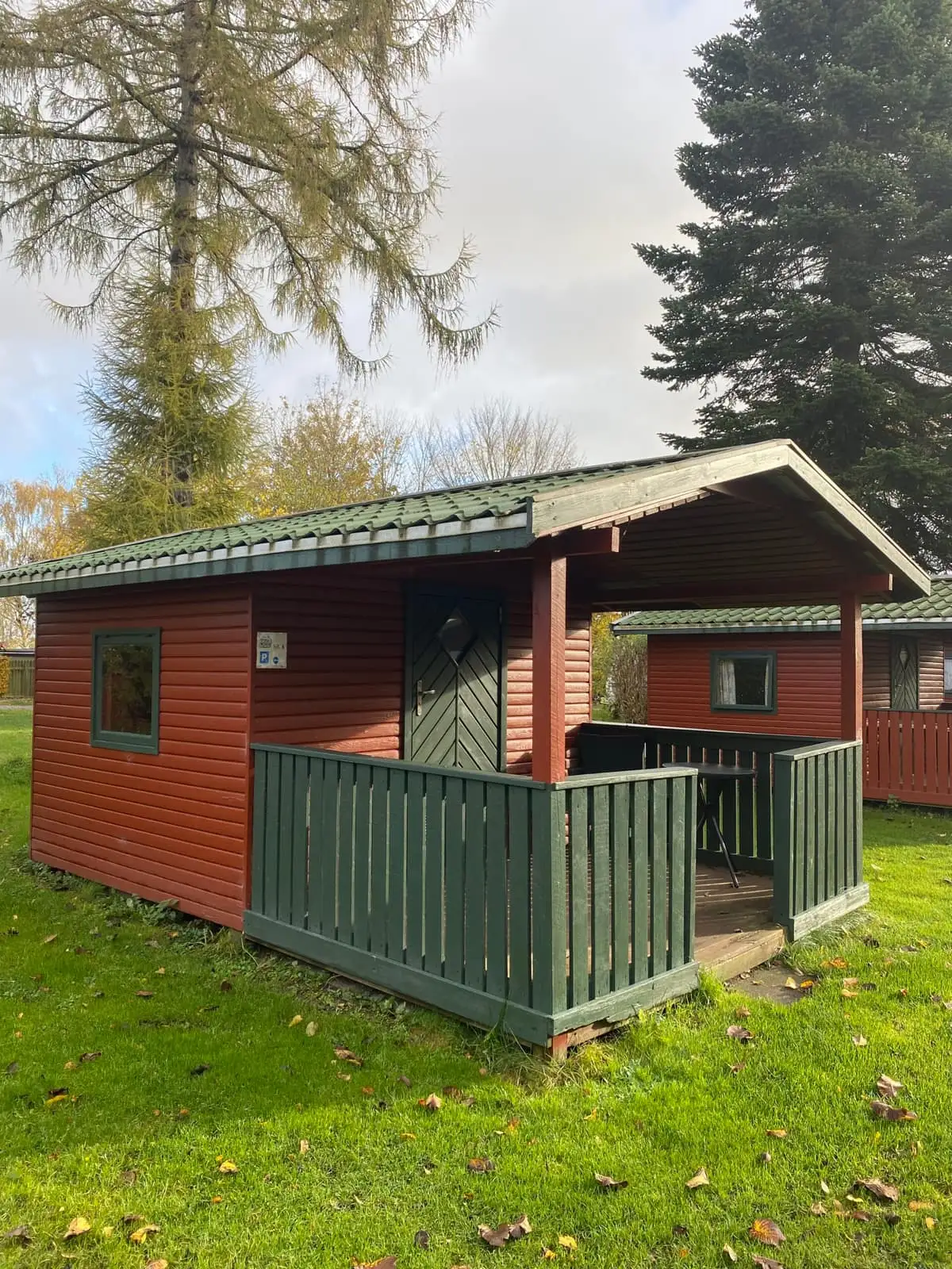 Rødt træhus med grøn terrasse, en af pladsens hytter