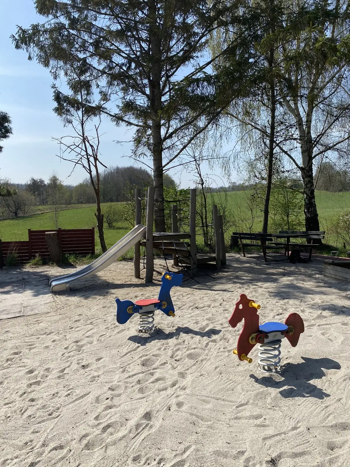 Legepladsen med rutsjebane og vippedyr og udsigt over marken